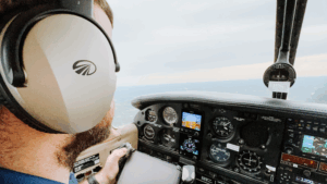 Pilot inside a small aircraft cockpit in flight, showcasing flight instruments and navigation displays—an immersive look into aircraft ownership.