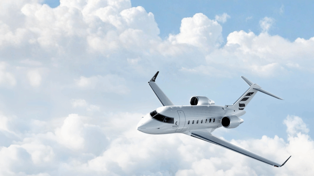 A sleek Bombardier business jet cruising above white clouds in a bright blue sky, showcasing its aerodynamic design and luxury appeal.